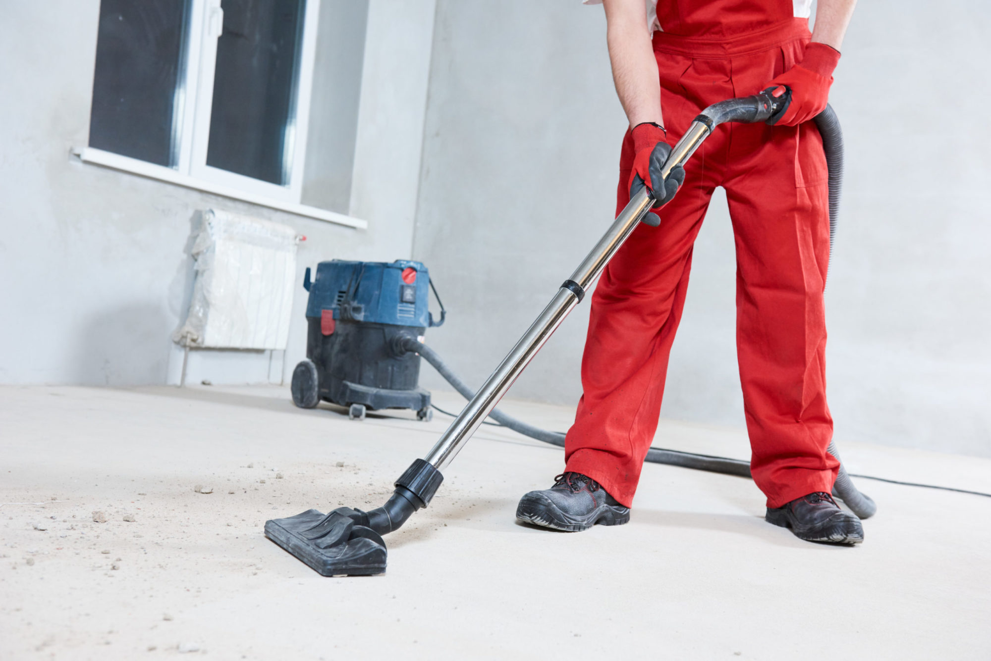 worker cleaning and removing construction dust with vacuum cleaner after repair